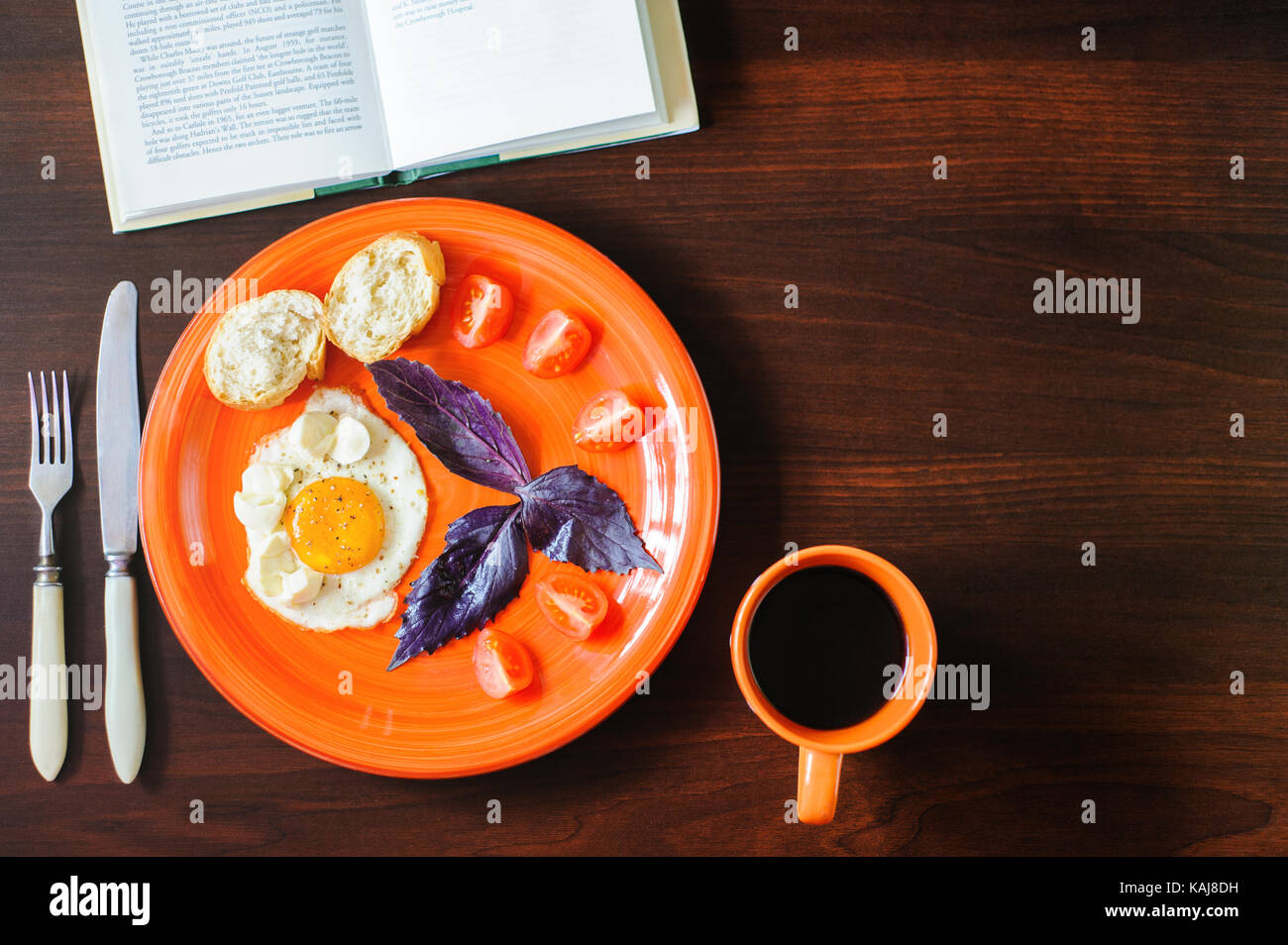 fried eggs mozzarella with basil and tomatoes on orange plate Stock