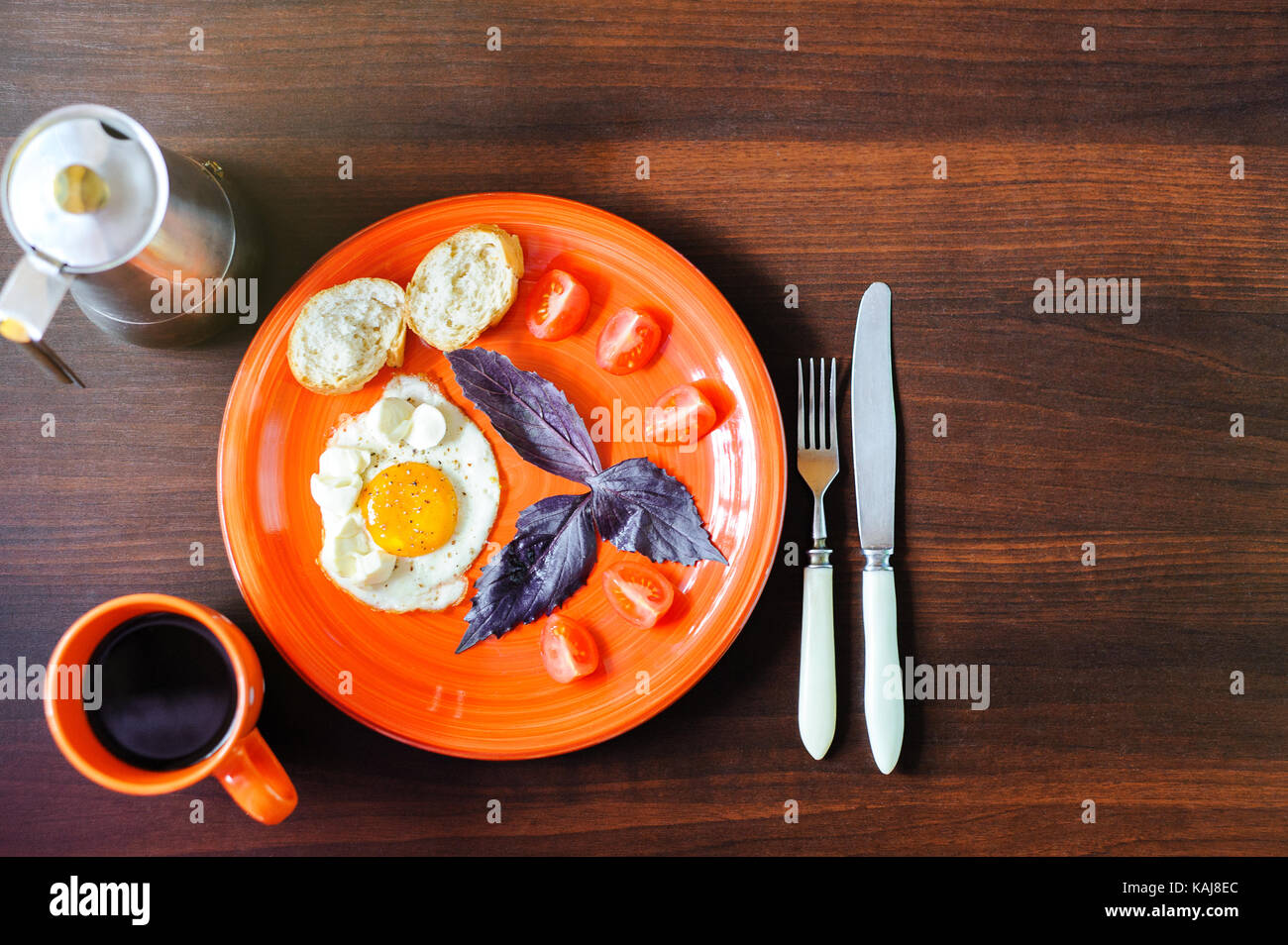fried eggs mozzarella with basil and tomatoes on orange plate Stock