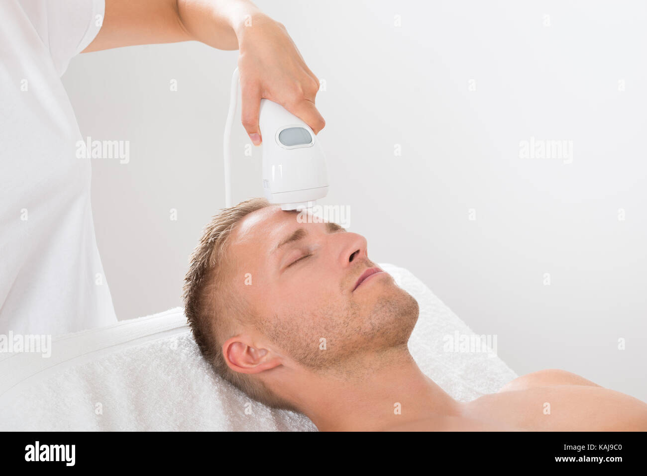 Young Man Receiving Laser Hair Removal Treatment At Beauty Center