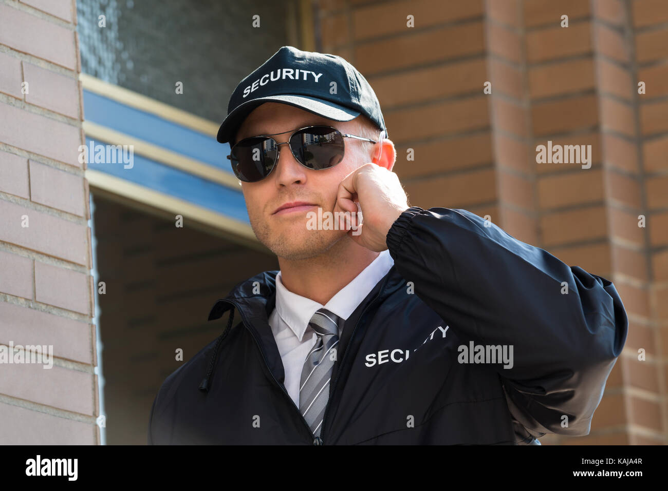 Close-up Of Security Guard Standing In Front Of The Entrance Listening To Earpiece Stock Photo