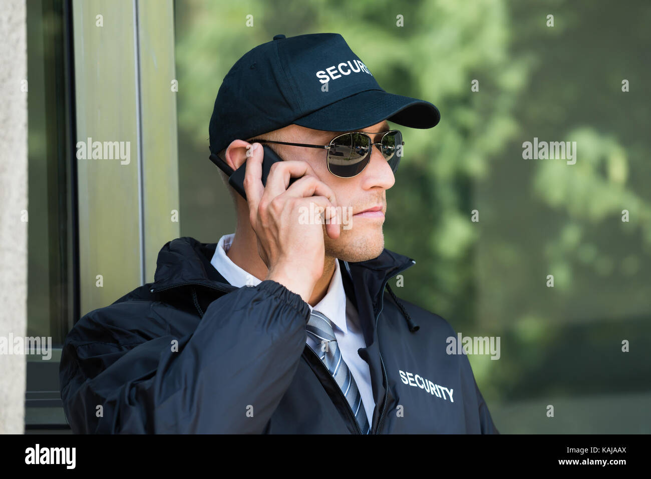 Portrait Of Young Security Guard Talking On Walkietalkie Stock Photo