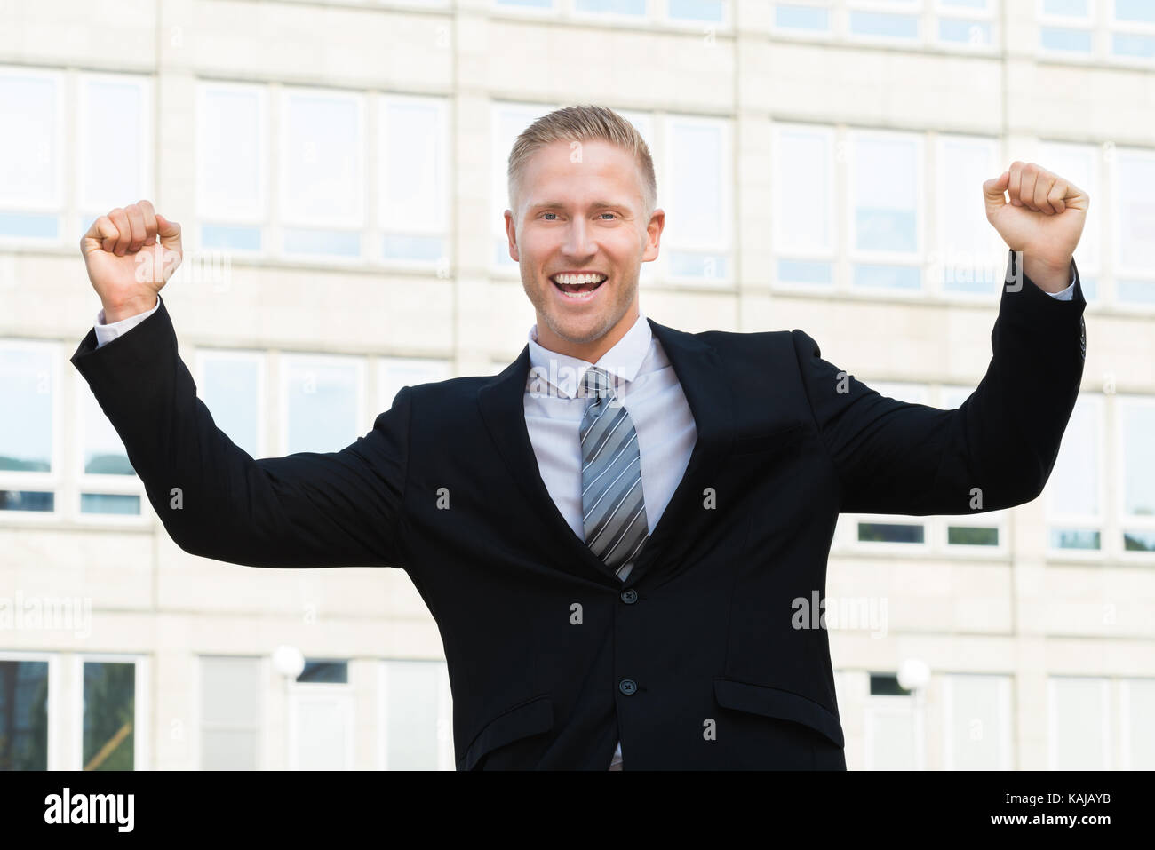 Excited And Smiling Businessman With Raised Arm Stock Photo - Alamy