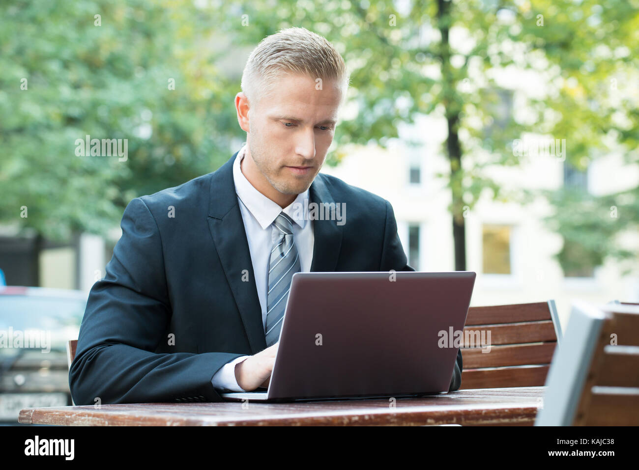 Young Businessman Sitting On Bench Using Laptop Stock Photo - Alamy