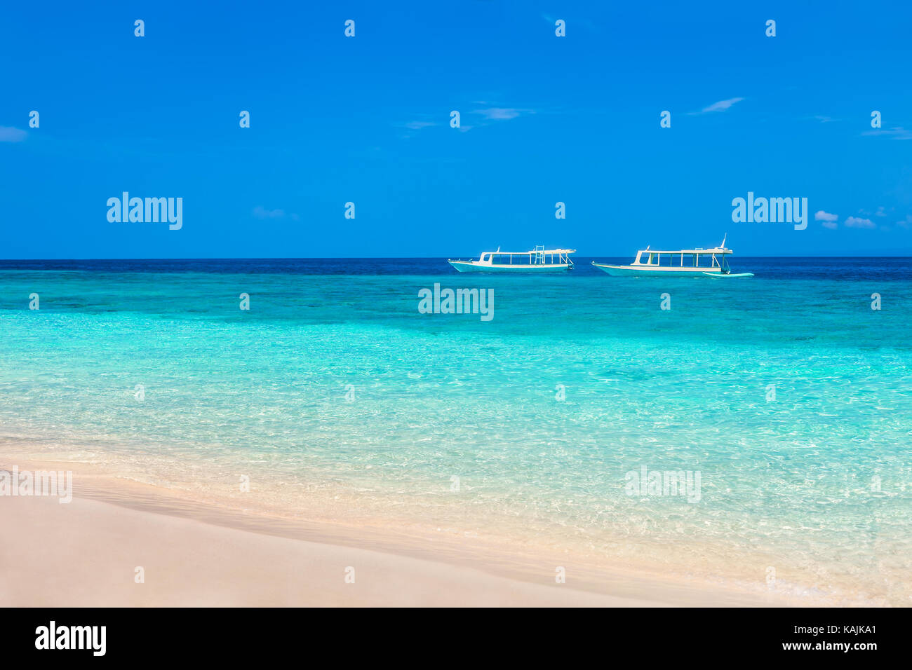 Beautiful beach and tropical turquoise sea with boats on horizon. Vacation Stock Photo