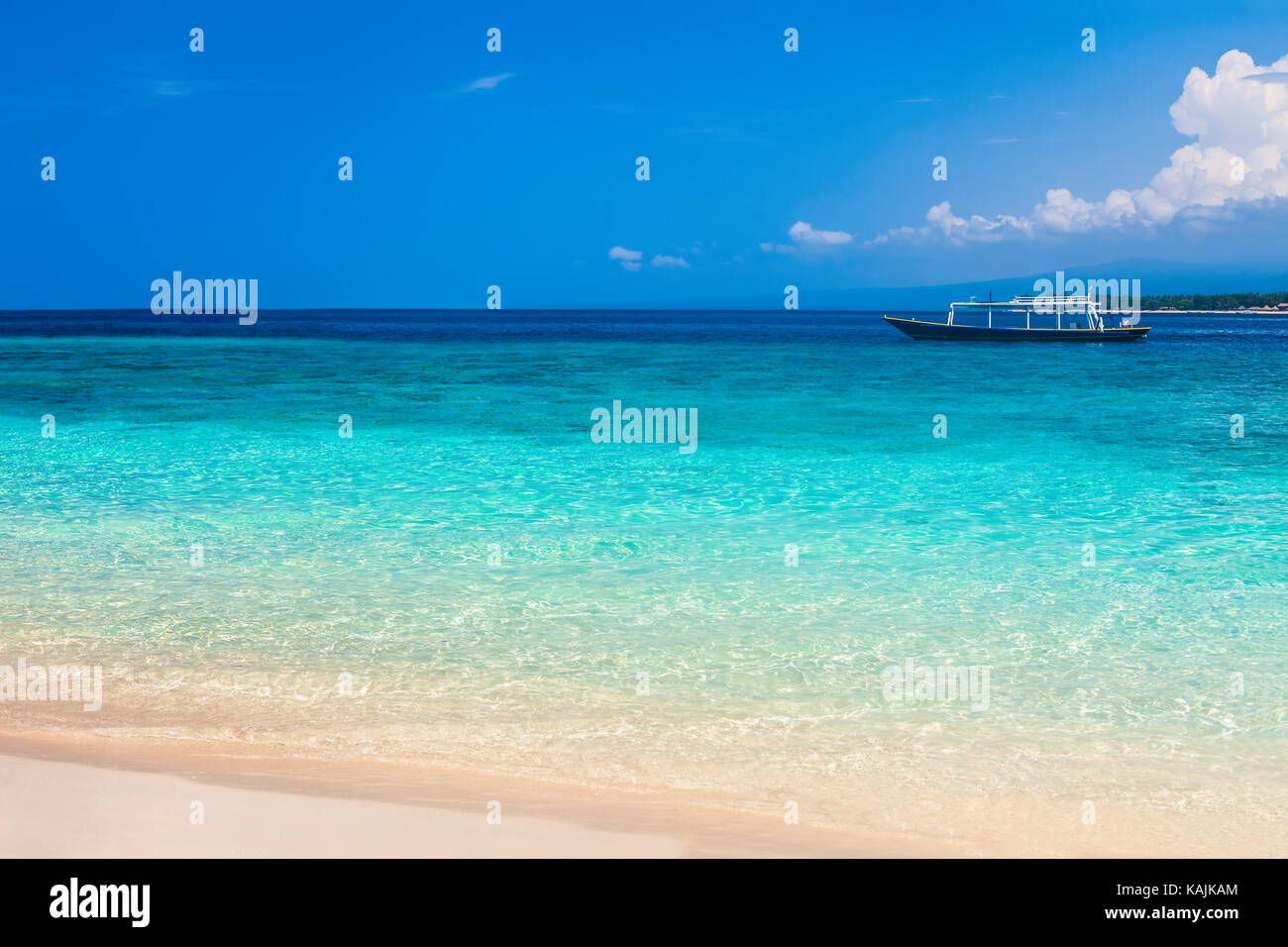 Beautiful beach and tropical turquoise sea with boat on horizon. Vacation Stock Photo