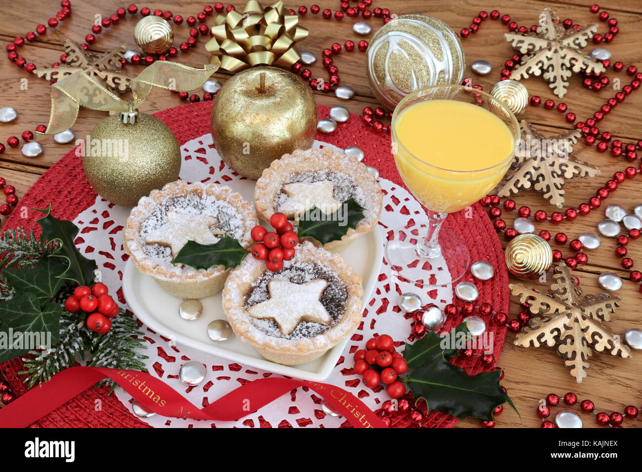 Mince pies with holly on a heart shaped plate with eggnog drink, gold ...