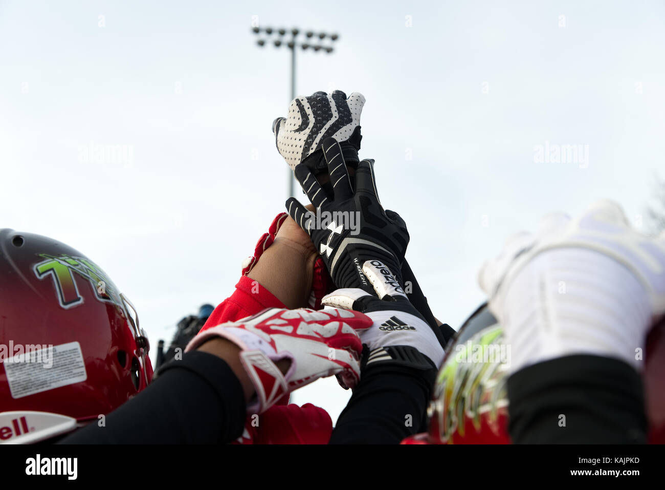 Philadelphia, PA, USA - November 30, 2013; Players of a high school football team hold hands high ahead of a championship game. Stock Photo