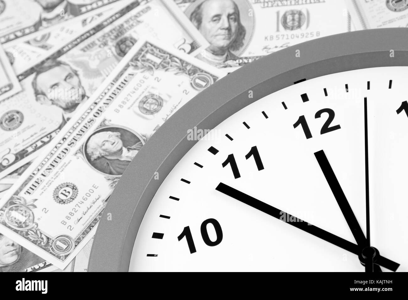 Clock on assorted American banknotes. Time is money idea Stock Photo