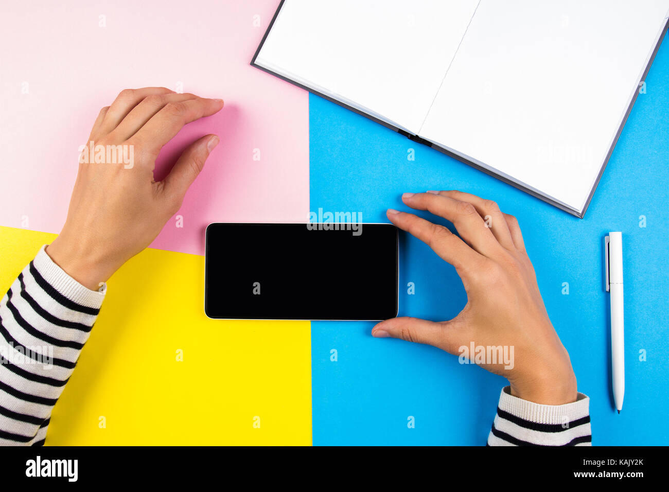 Notebook Open. Phone Female hands with mobile smart phone and open notebook over yellow ...