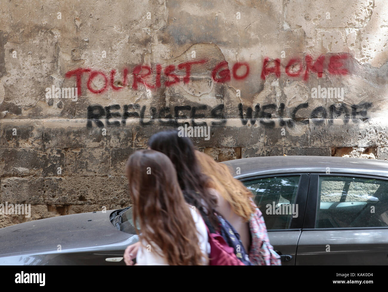 Wall paintings reading 'Tourists go home' and lower in catalan 'abolition holiday rentals housing' are pictured in a central street downtown Palma Stock Photo