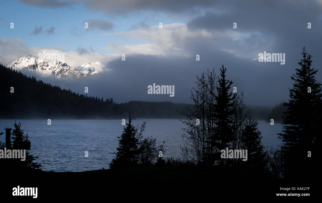 View over Spruce Lake towards Dickson Range (South Chilcotin Mountain Park, BC, Canada) with clouds rising in the early morning. Stock Photo