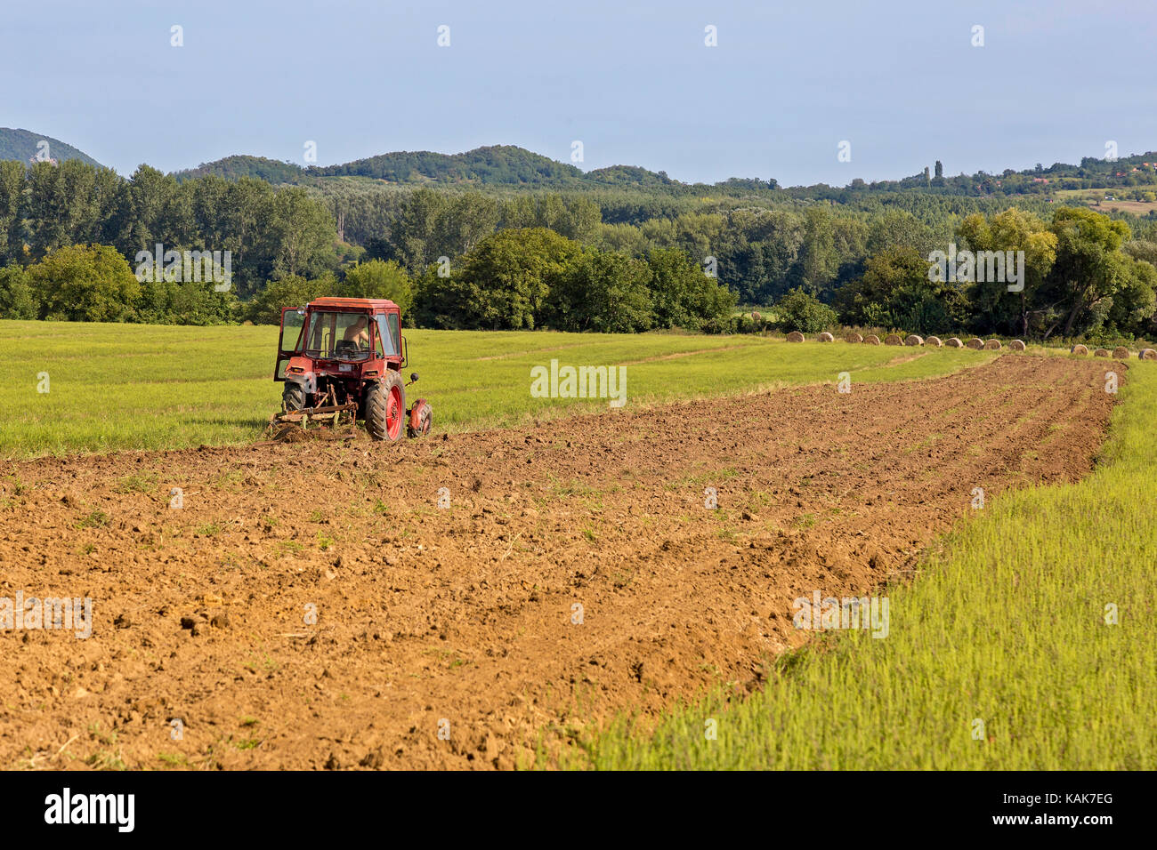Old tractor working on the field Stock Photo - Alamy