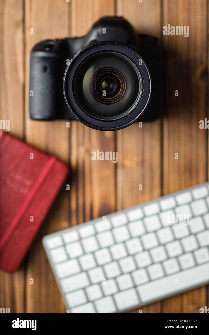 Professional digital camera and computer keyboard on wooden table Stock