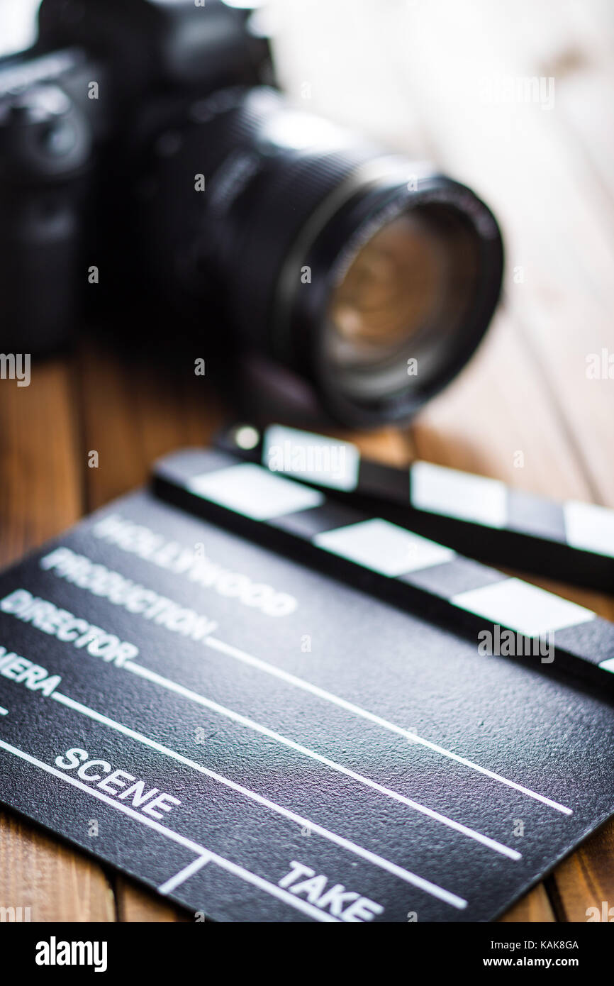 Professional camera and clapper board on wooden table. Stock Photo