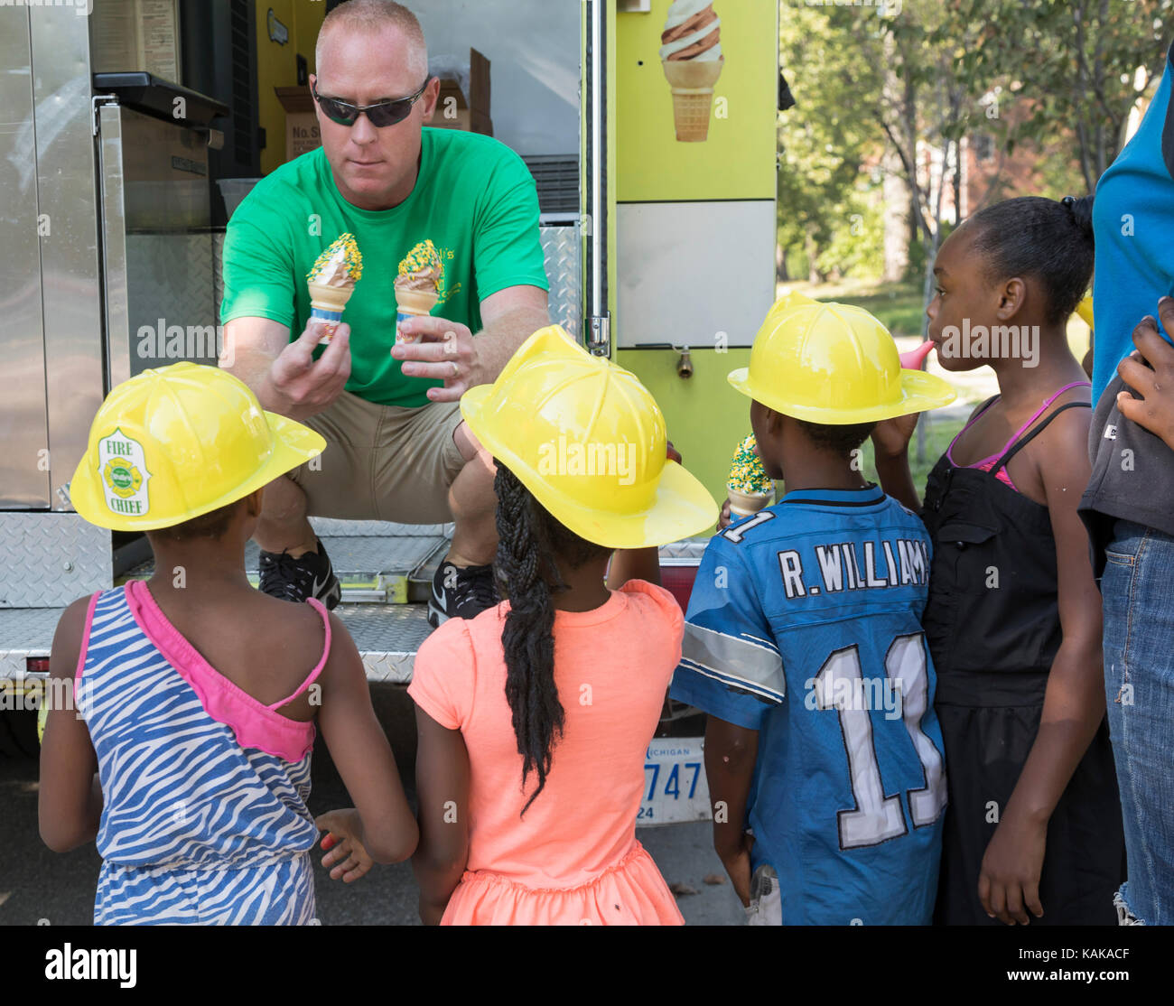 Detroit, Michigan - Children get cones of frozen custard from an old fire truck at a block party in the Morningside neighborhood. Stock Photo