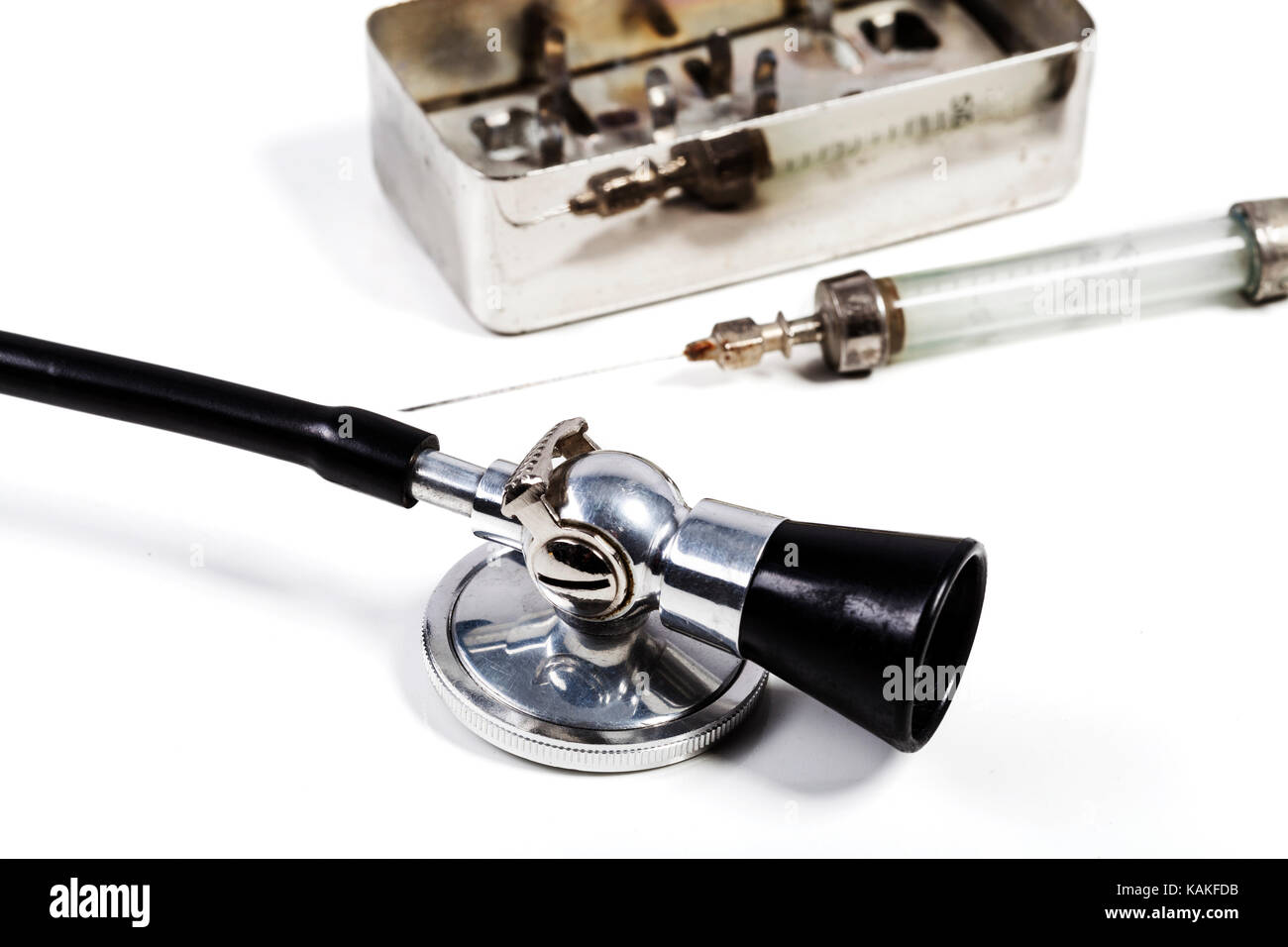 Old Glass Syringe with needle and black stethoscpe isolated on white background Stock Photo