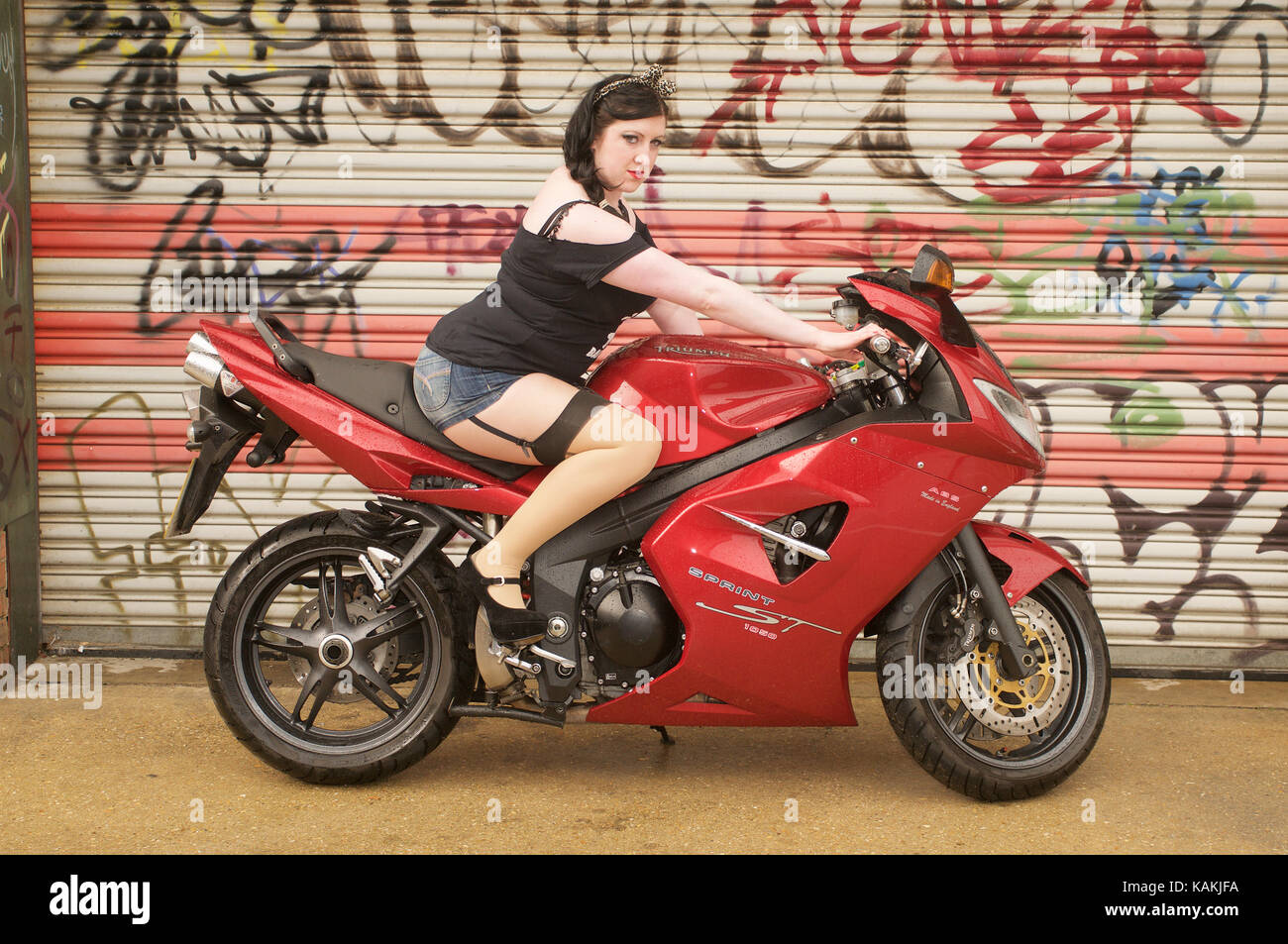 Pretty girl and a Triumph Sprint 1050 motorcycle in an urban location Stock  Photo - Alamy