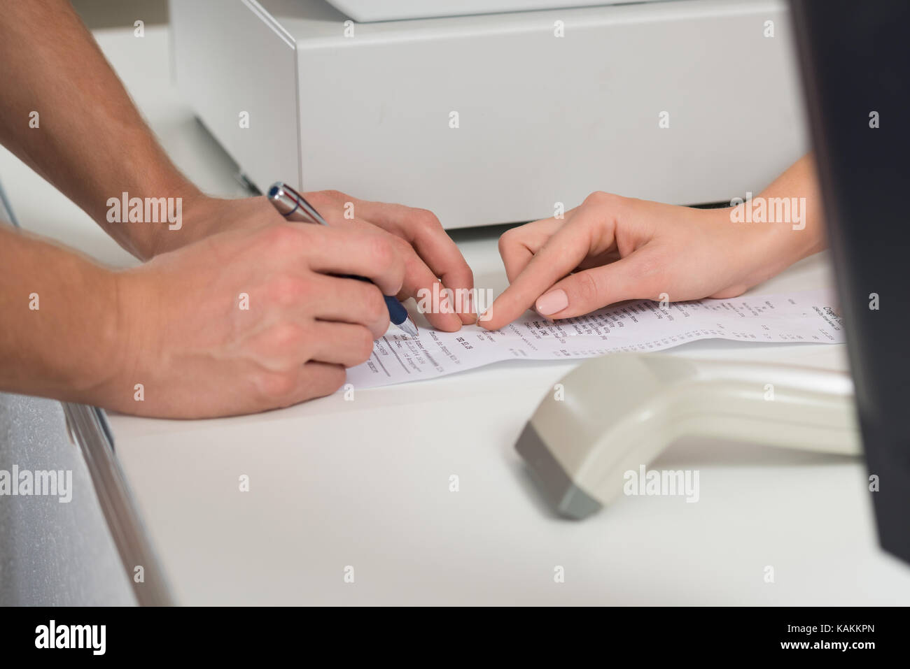 Cropped image of customer's hands signing on receipt at counter in store Stock Photo