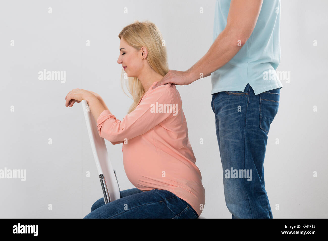 Midsection of man giving shoulder massage to pregnant woman over white background Stock Photo