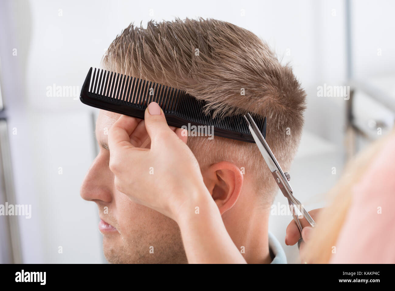 Young man getting haircut from female hairdresser at salon Stock Photo