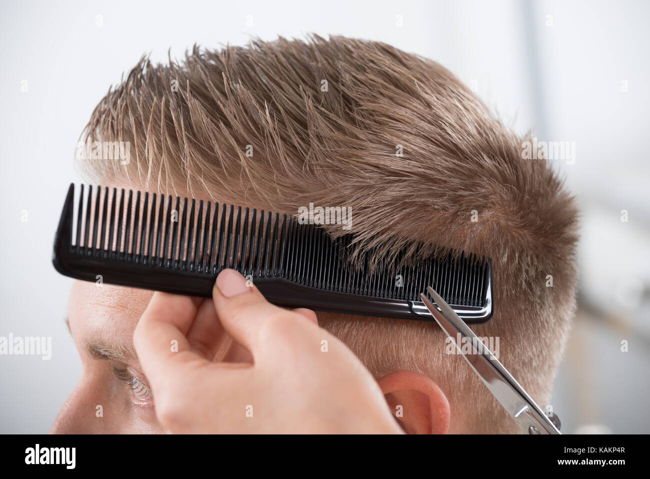 Young man getting haircut from female hairdresser at salon Stock Photo