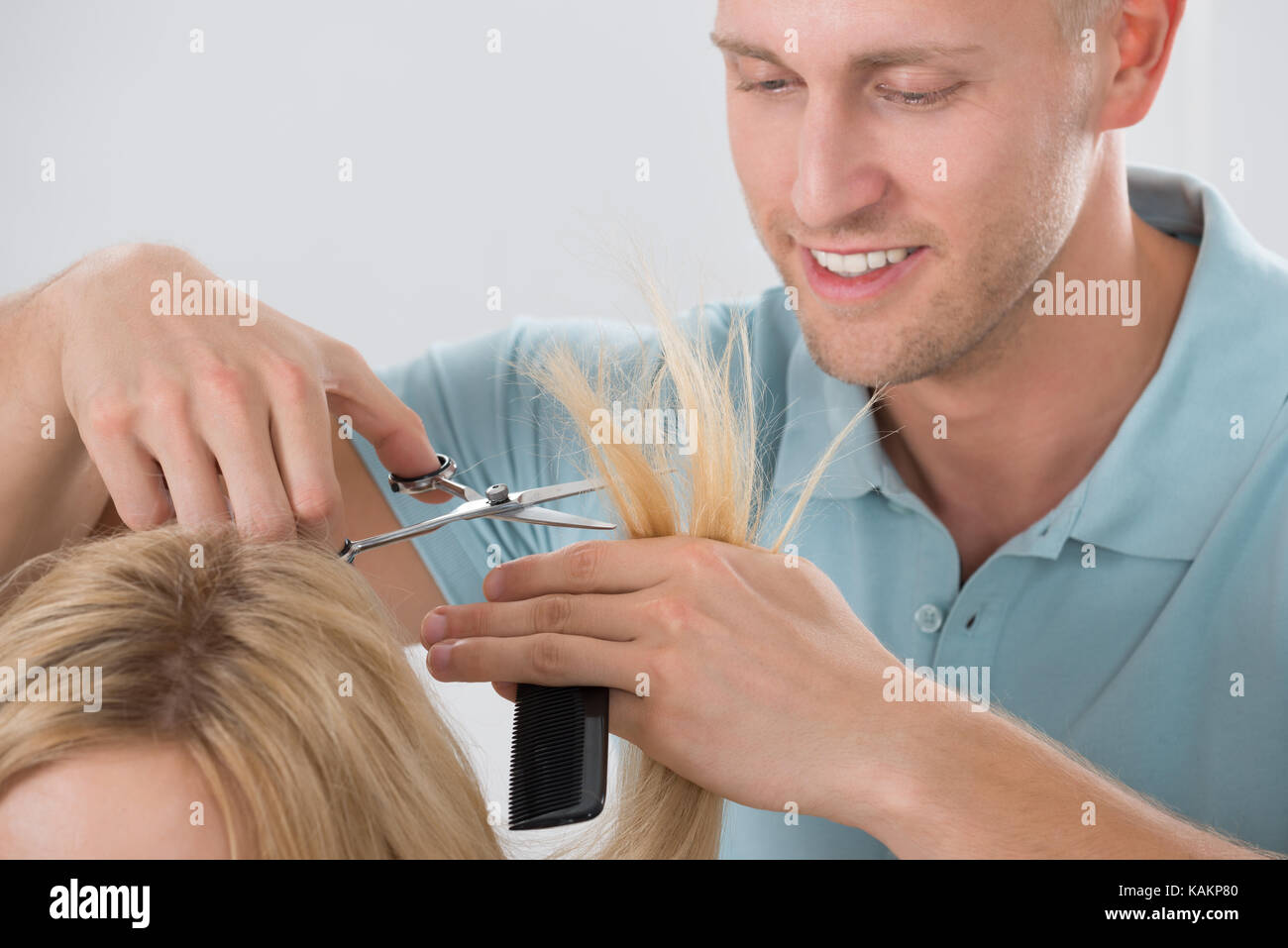Happy young male hairdresser cutting customer's hair at salon Stock Photo