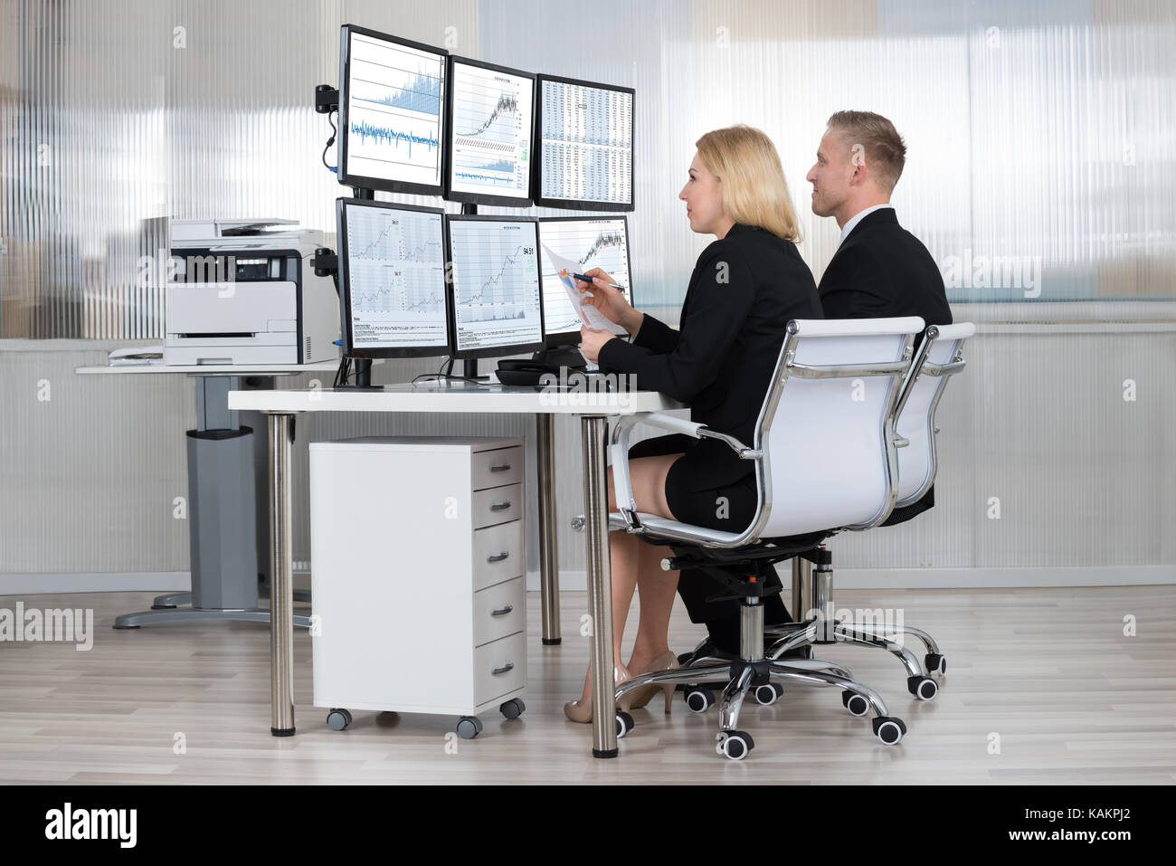 Financial workers analyzing data displayed on computer screens at desk ...