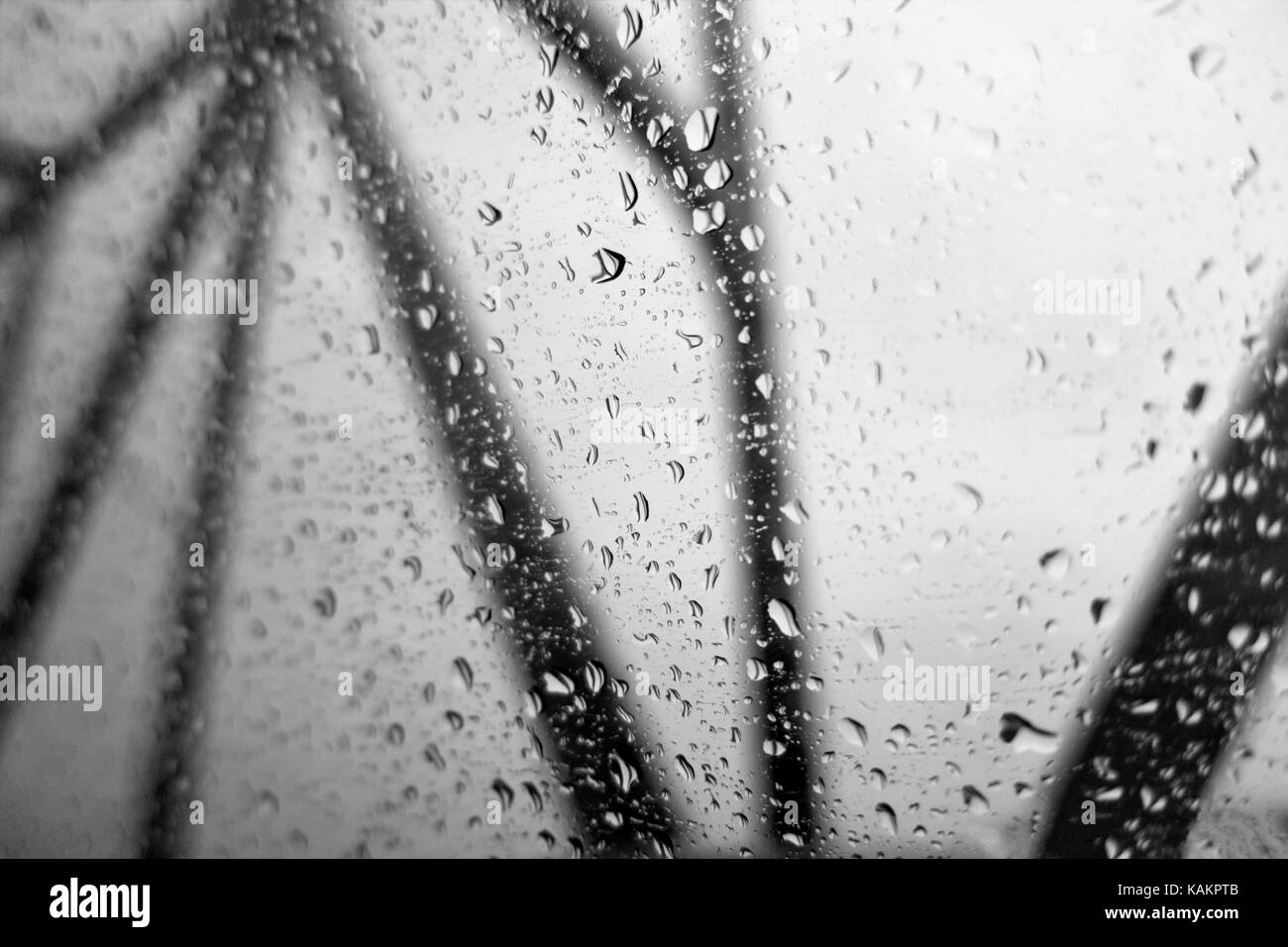Looking out of windows covered with water droplets at black bridge struts on a gray sky. Concept. Stock Photo