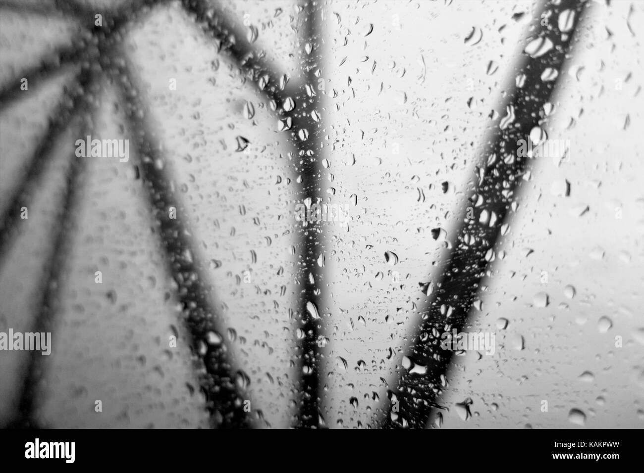 Looking out of windows covered with water droplets at black bridge struts on a gray sky. Concept. Stock Photo