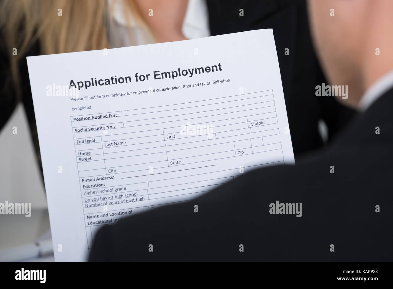 Male candidate holding application form in front of interviewer in office Stock Photo