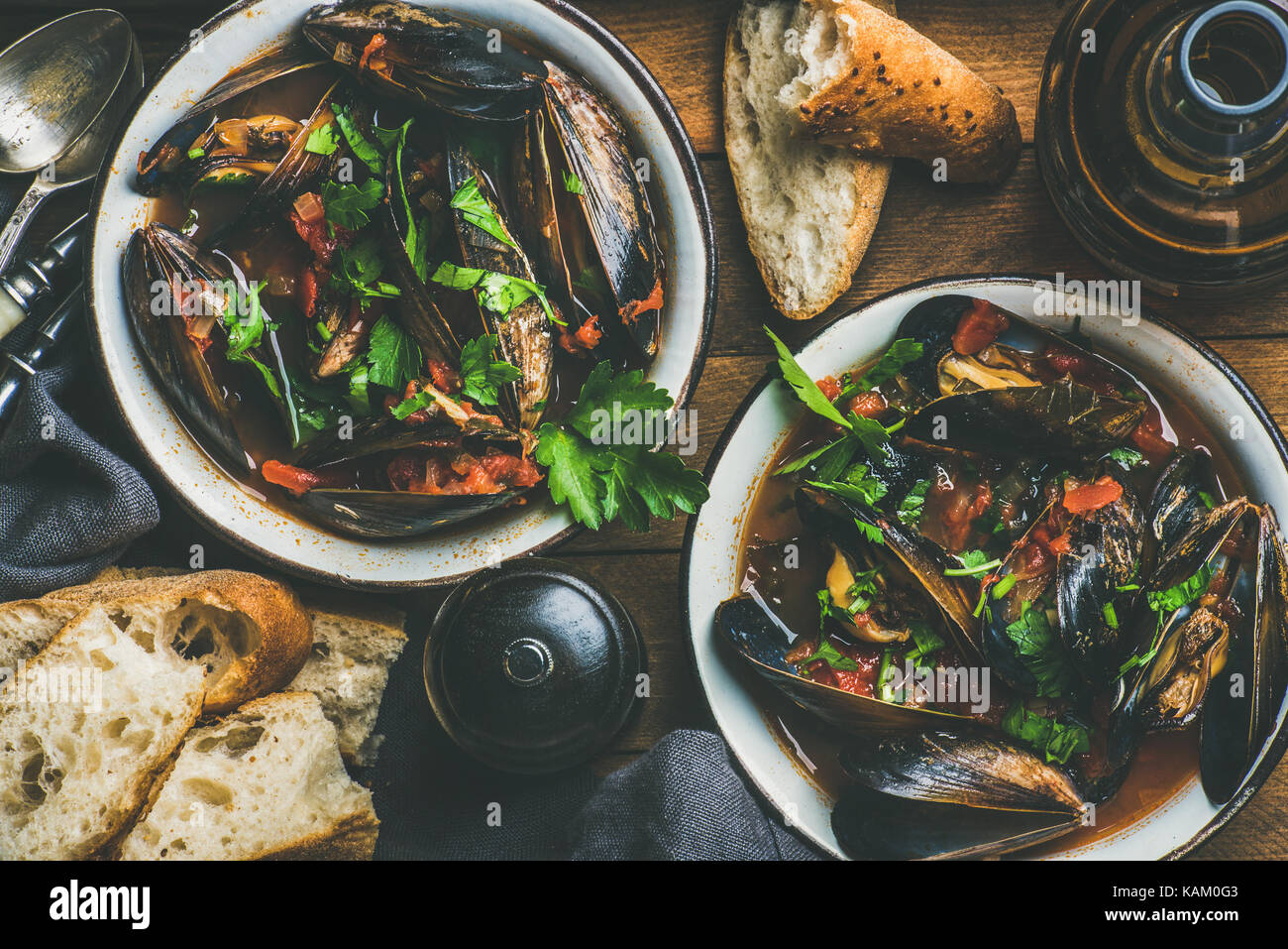 Boiled mussels in tomato sauce and beer over wooden background Stock