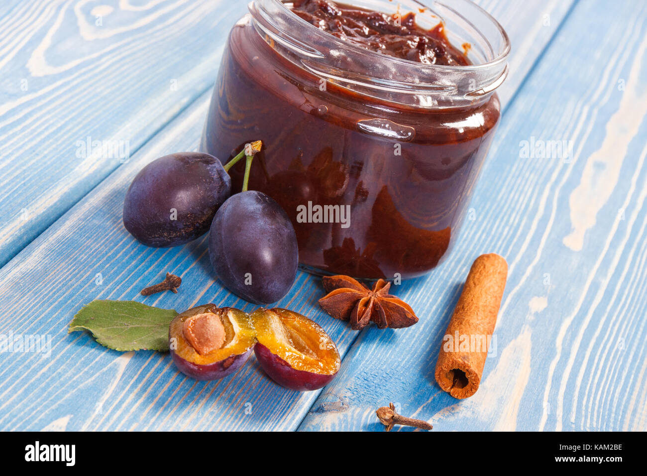 Fresh homemade plum marmalade in jar, ripe fruits and spices on wooden boards, concept of healthy sweet dessert Stock Photo