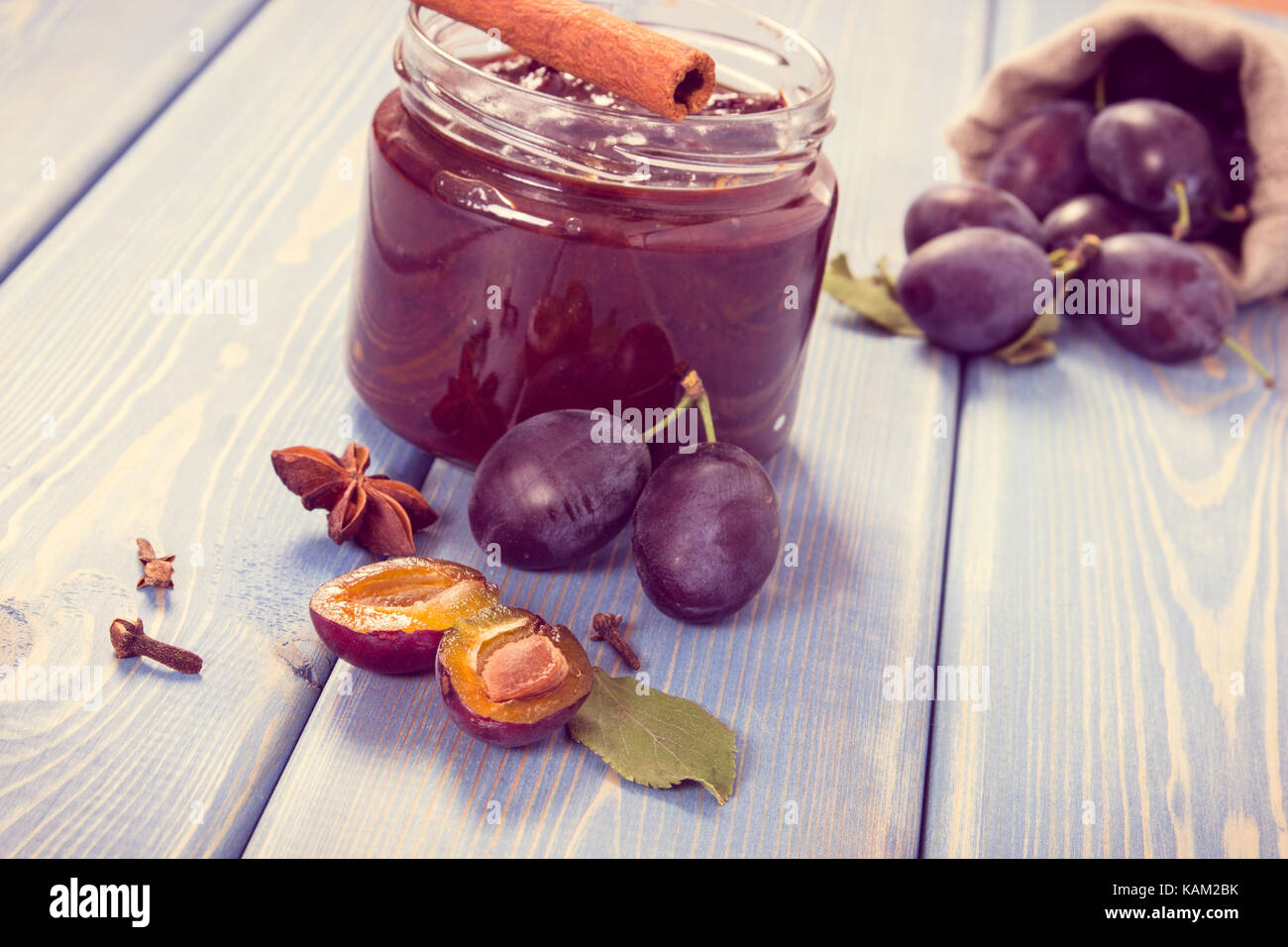 Vintage photo, Fresh homemade plum marmalade in jar, ripe fruits and spices on wooden boards, concept of healthy sweet dessert Stock Photo
