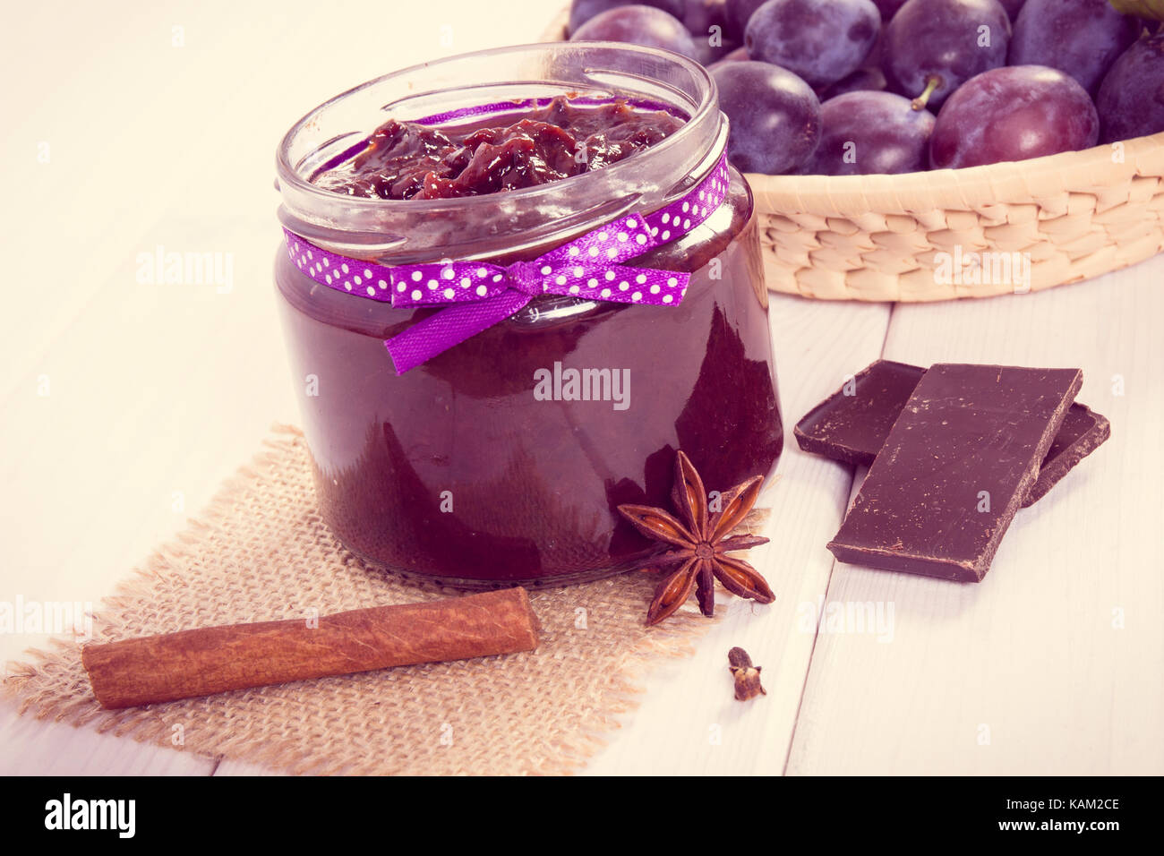 Vintage photo, Fresh plum jam or marmalade in glass jar, ripe fruits and chocolate, concept of healthy sweet dessert Stock Photo