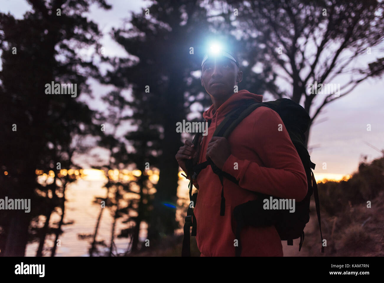 Young African man hiking alone in the woods at dusk Stock Photo