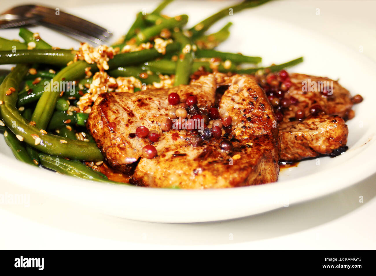 beef steak with black pepper, green beans with sesame on white plate