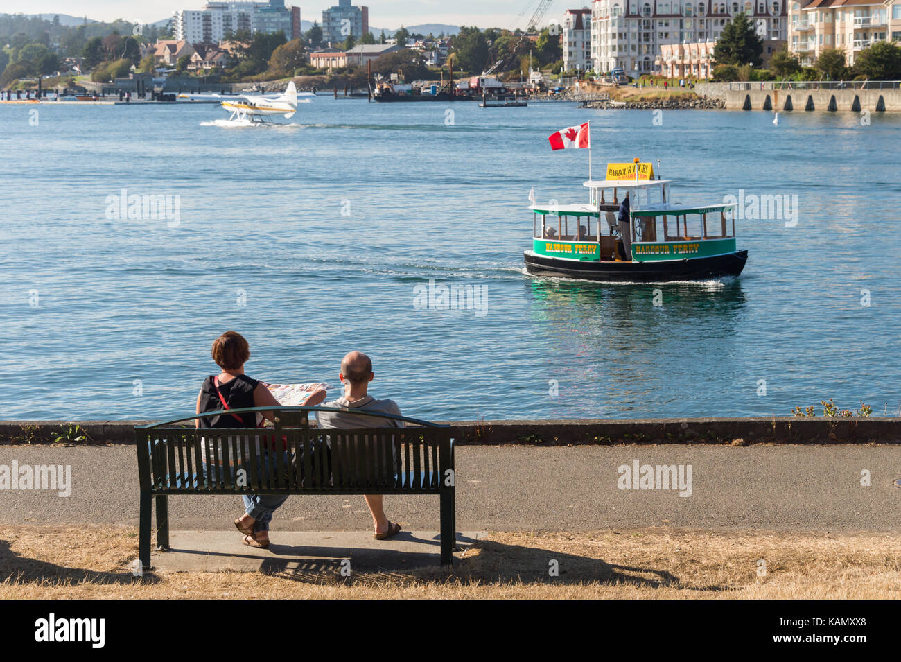 Victoria, BC, Canada - 11 September 2017: Couple looking at the Pacific Ocean from David Foster Way as a water taxi is passing by Stock Photo