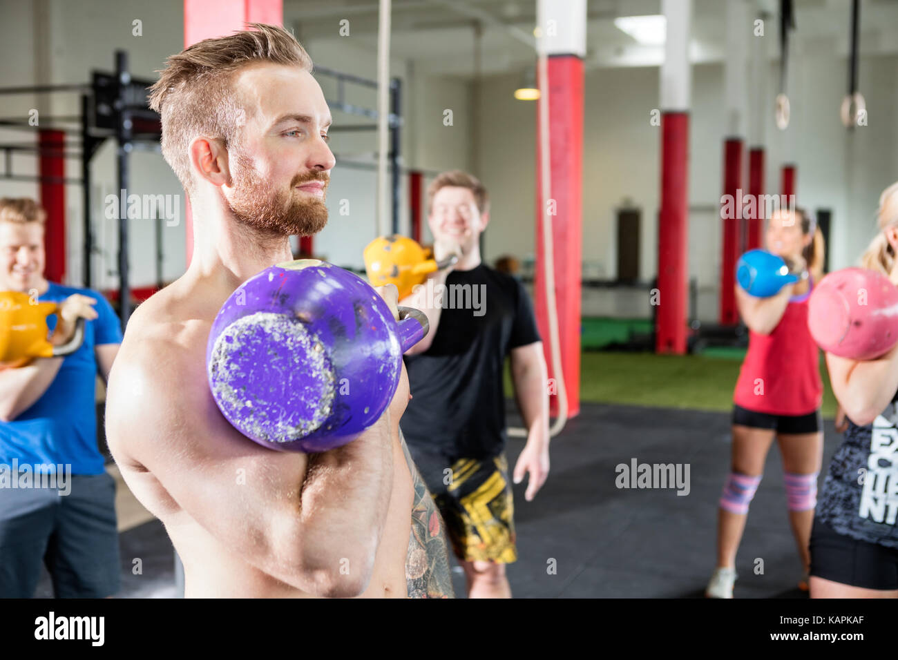 Male Instructor Lifting Kettlebell With Clients In Gym Stock Photo Alamy