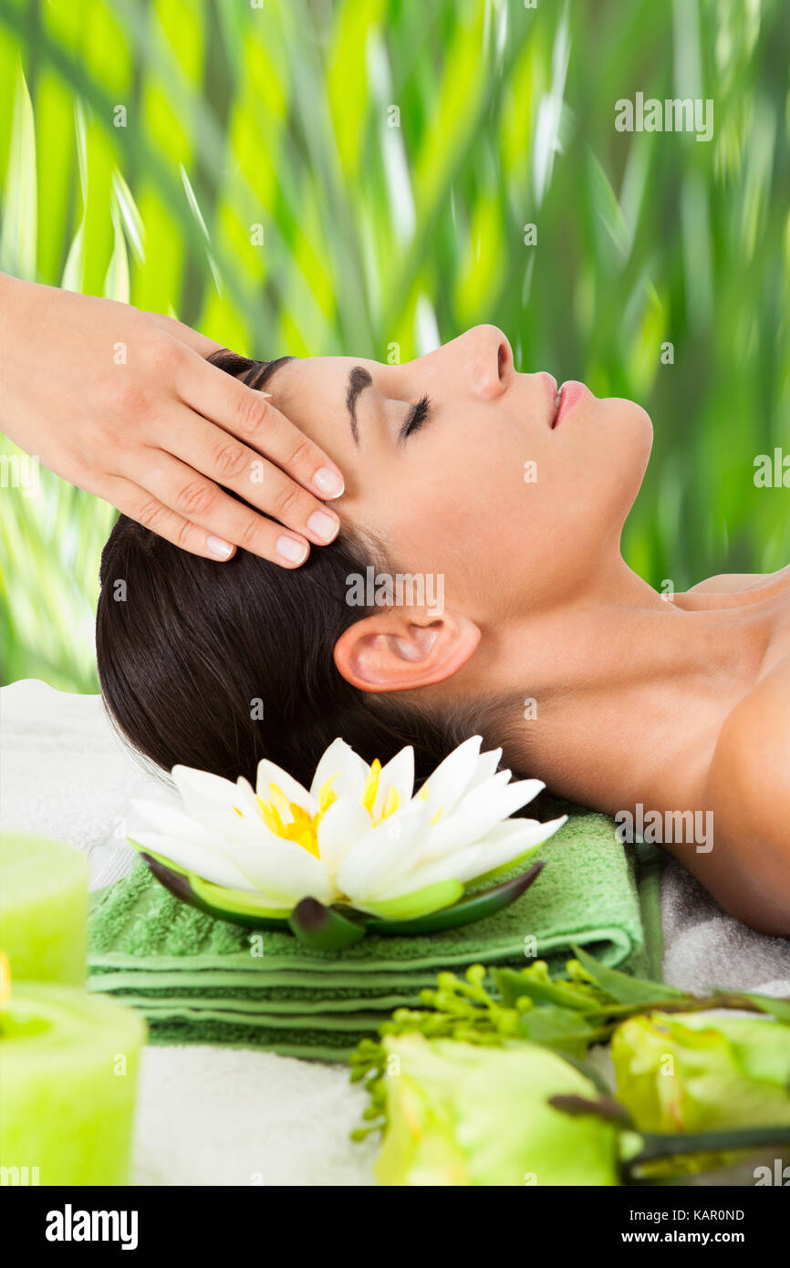 Side view of relaxed young woman receiving head massage at spa Stock