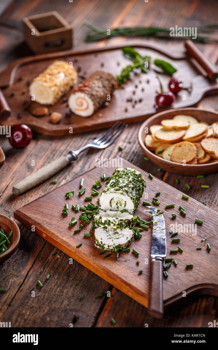 Cheese appetizer. Delicious soft cheese with fresh herbs served on a cutting board Stock Photo