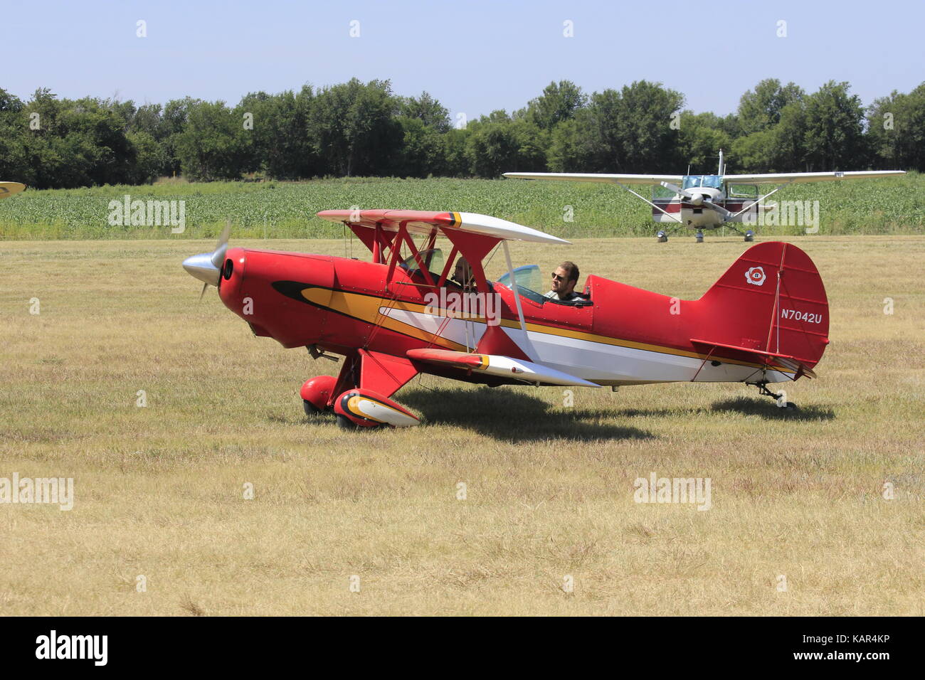 Red Airplane landing on a grass runway in Kansas. Stock Photo