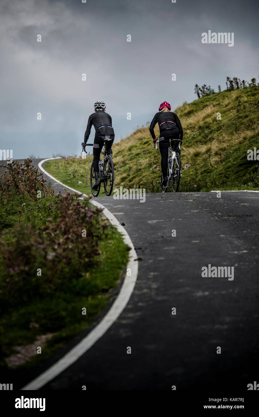 Cycling couple climbing Great Dun Fell in the Pennines, Cumbria, UK Stock Photo