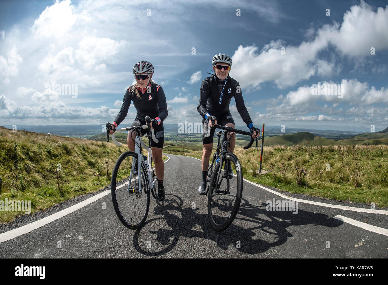 Cycling couple climbing Great Dun Fell in the Pennines, Cumbria, UK Stock Photo