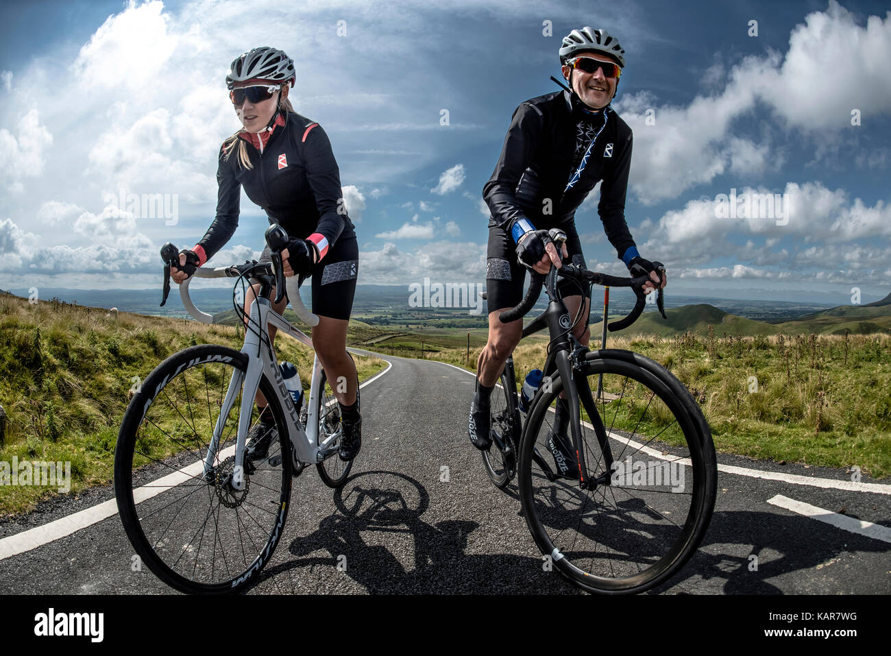 Cycling couple climbing Great Dun Fell in the Pennines, Cumbria, UK Stock Photo