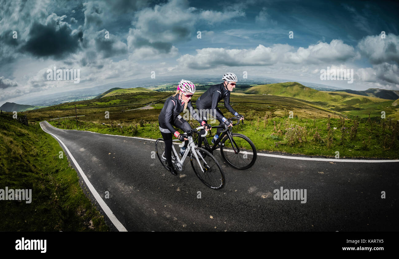 Cycling couple climbing Great Dun Fell in the Pennines, Cumbria, UK Stock Photo