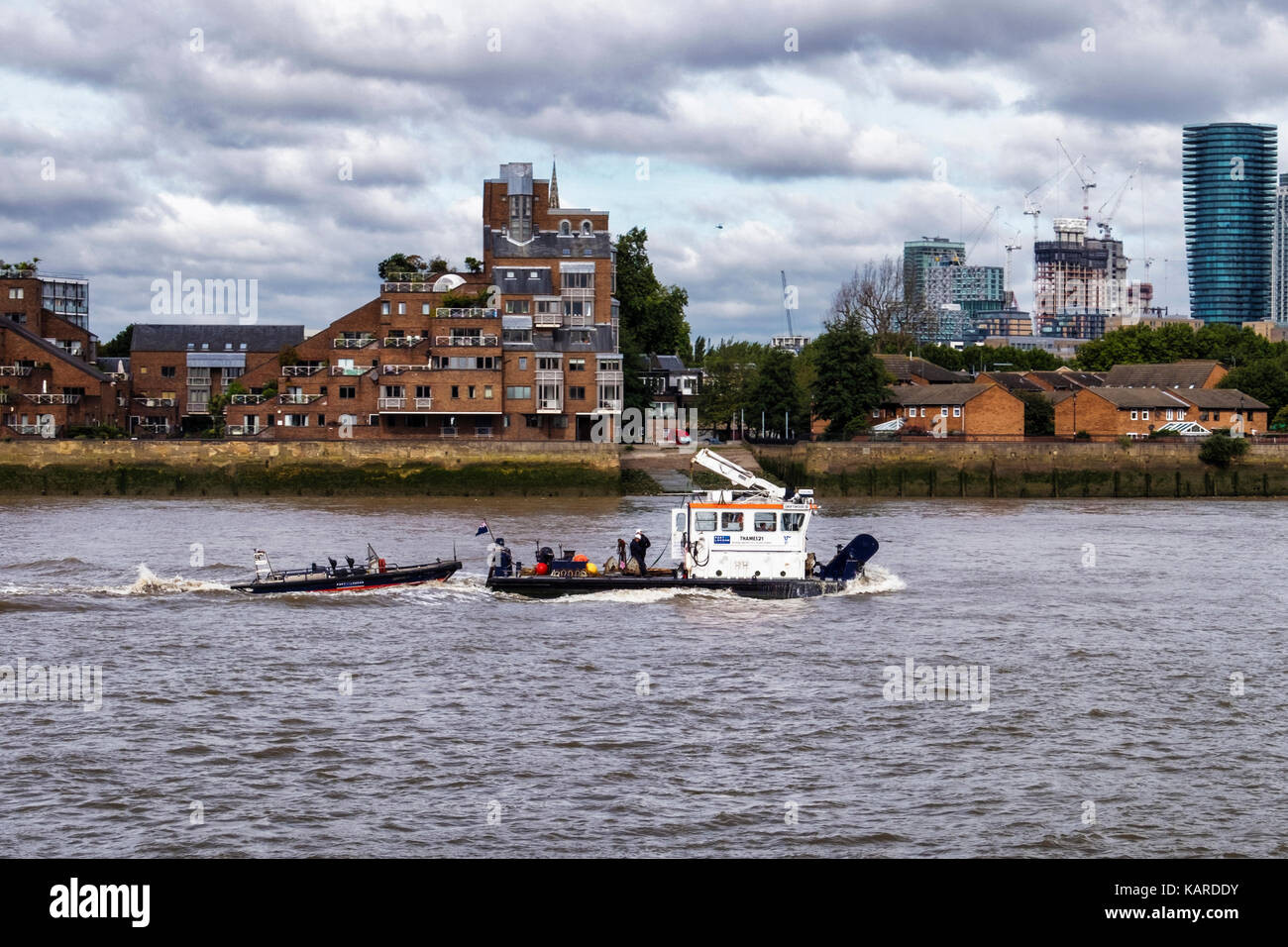 Thames river view with tug boat on choppy water and new and old apartment buildings on bank of river Stock Photo