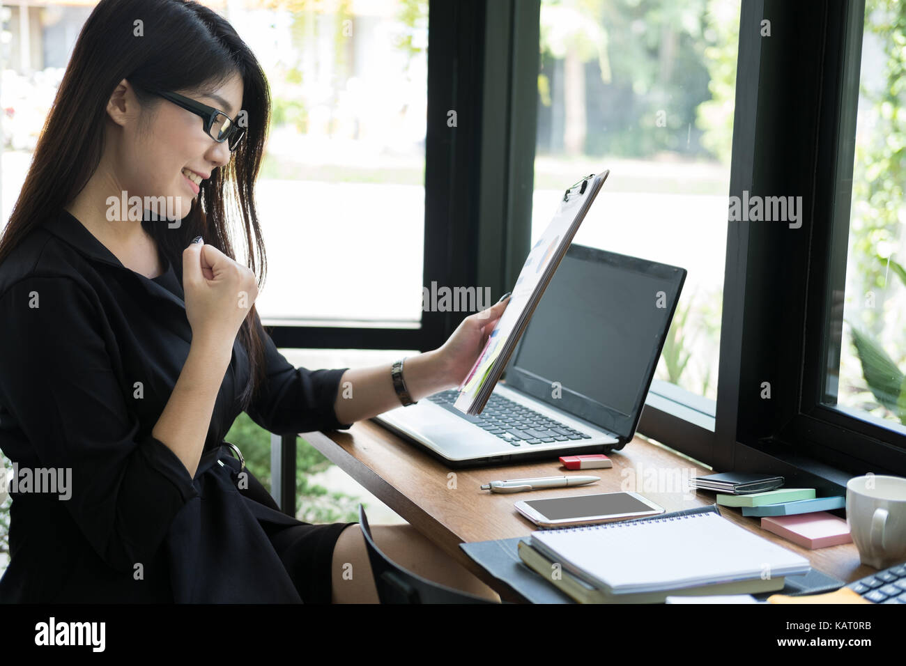 businesswoman glad with successful project at workplace. young happy woman work with new business plan at office. female manager raise her fist with g Stock Photo