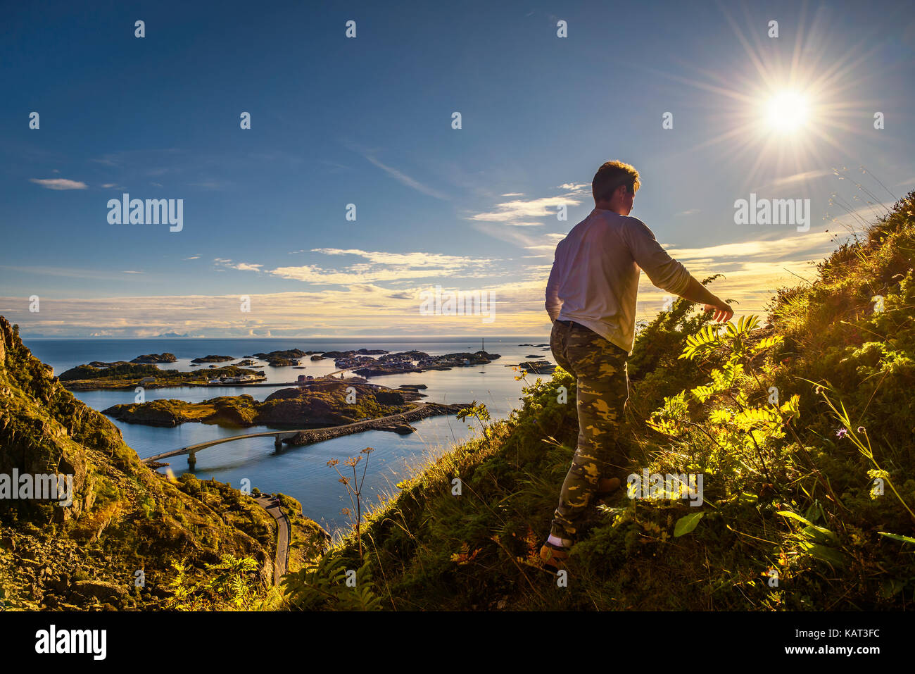 Male hiker going to the top of mount Festvagtinden with views over the village of Henningsvaer on Lofoten islands in Norway Stock Photo