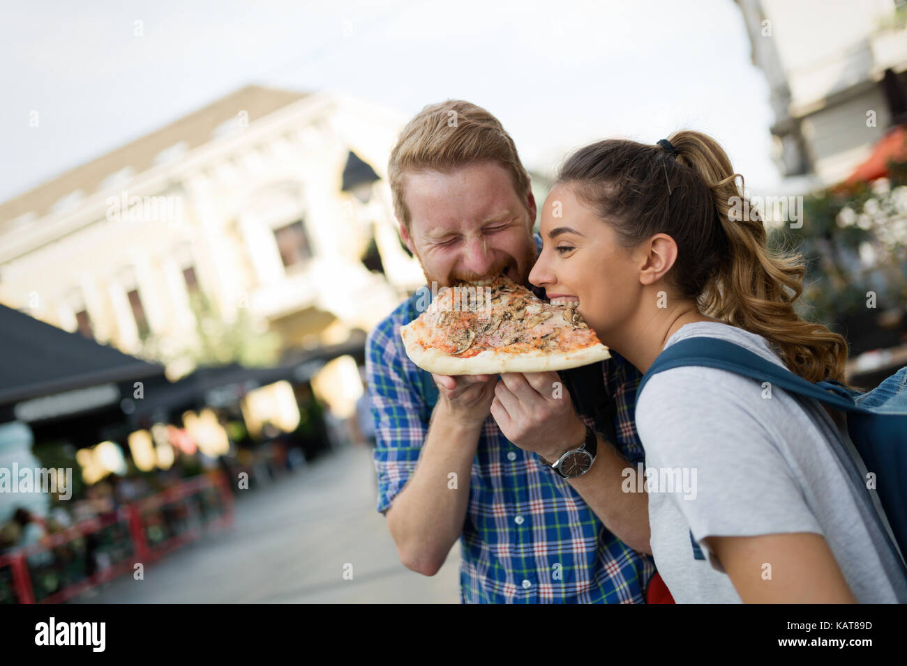 Happy couple sharing pizza on street Stock Photo