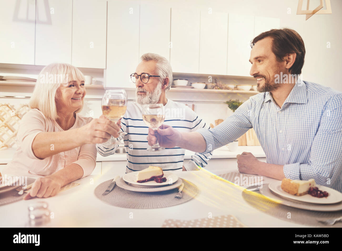 Positive adult man drinking wine with his aged parents Stock Photo - Alamy